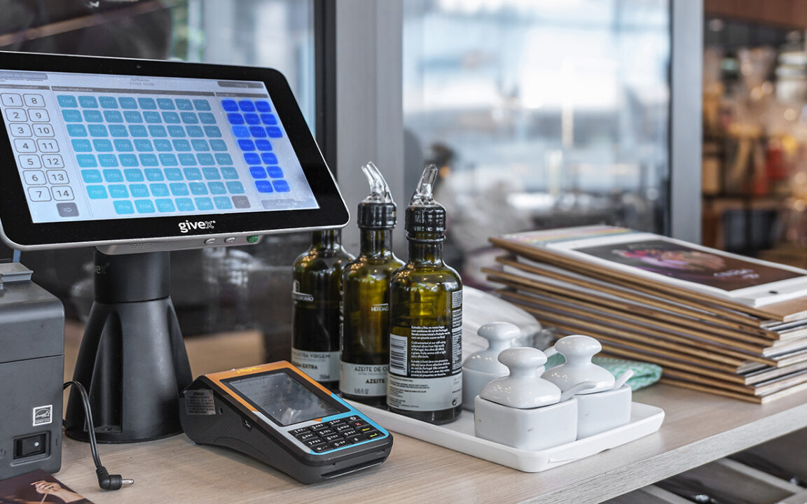 image shows a Givex payment terminal with various FOH items on the table beside it