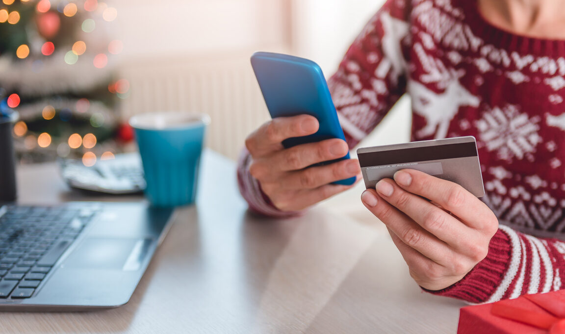 Person in holiday sweater making an online purchase in Holiday environment