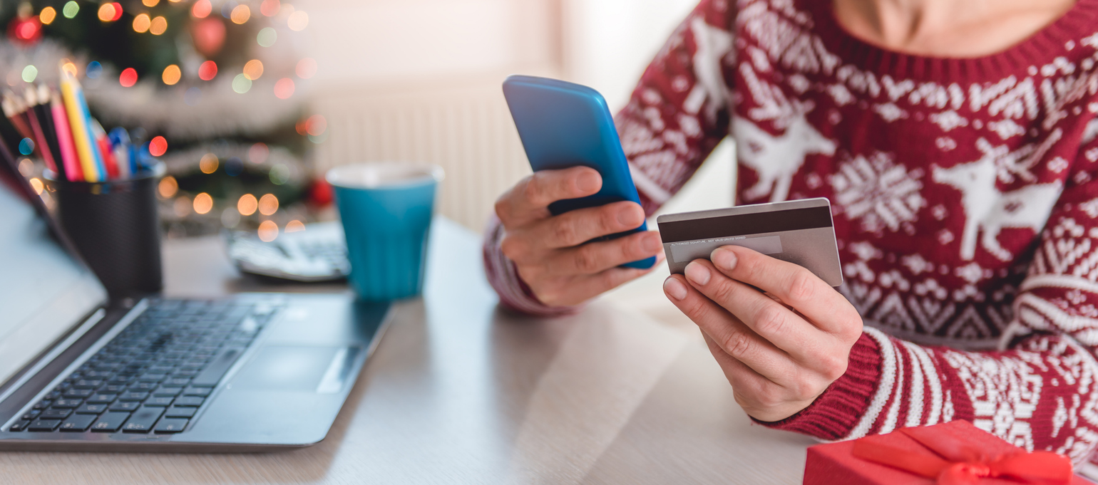Person in holiday sweater making an online purchase in Holiday environment